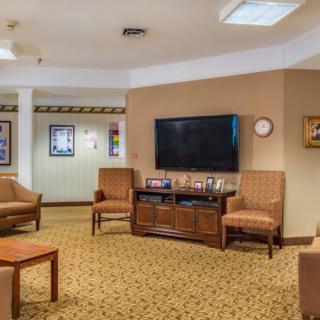 A cozy living room with a television, chairs, and a coffee table on a carpeted floor.