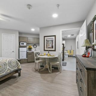 A cozy studio apartment interior with a bedroom, kitchenette, and dining area.
