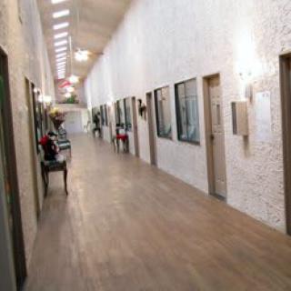 A long hallway with wooden flooring and doors along the sides.