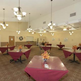 A spacious dining room with elegantly set tables and decorative chandeliers.