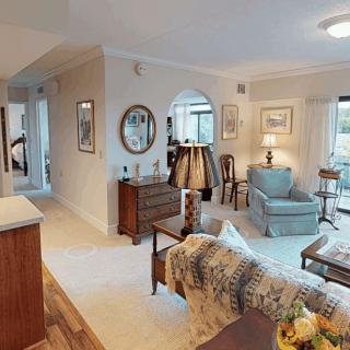 A cozy and elegantly furnished living room with various seating options, warm lighting, and tasteful decor.
