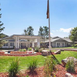A scenic view of a building surrounded by well-maintained gardens and a flagpole on a sunny day.