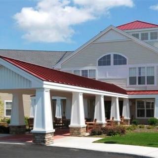 A residential building with a red roof and prominent entrance featuring columns.