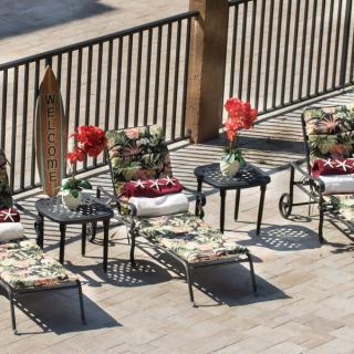 An inviting patio setup with lounge chairs and tables adorned with floral cushions and decorative flowers.
