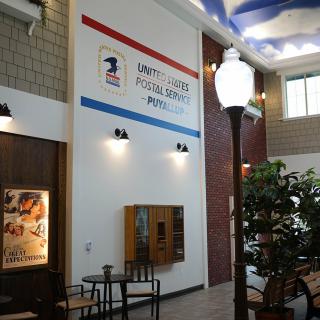 Interior of a United States Postal Service post office lobby with seating and lighting.