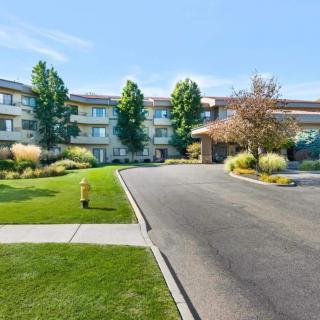 A modern residential building surrounded by well-maintained greenery and a paved driveway.