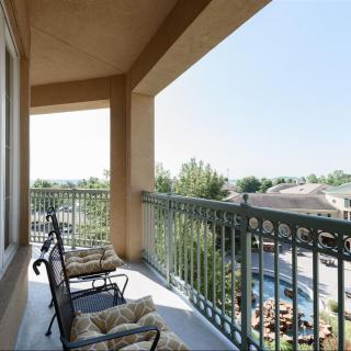 A sunny balcony with comfortable chairs overlooking a scenic view.