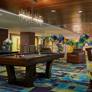A modern indoor lounge featuring a pool table, colorful carpet, and decorative balloons.