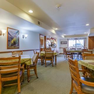 An inviting dining room with wooden tables and chairs arranged neatly, illuminated by overhead lighting.