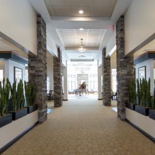 A modern hallway with stone accents and greenery leading to a sunlit area.