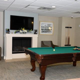 A cozy billiard room featuring a pool table, fireplace, and television.