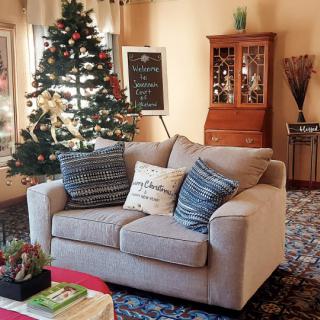 A cozy living room decorated for the holidays with a Christmas tree and a comfortable beige sofa adorned with cushions.
