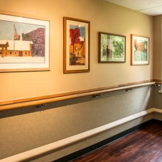 A hallway adorned with framed paintings and a handrail along the wall.