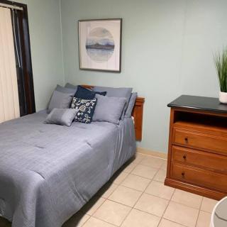 A cozy bedroom with a neatly made bed, wooden dresser, and minimalist decor.