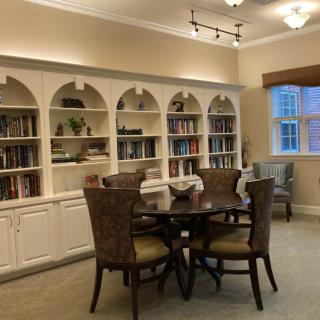 A cozy library room with bookshelves, a round table, and chairs.