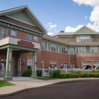 A brick healthcare facility with a prominent entrance, photographed during the day.