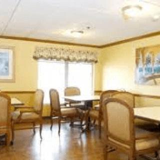 A cozy dining area with tables and chairs, decorated with wall art and natural light from the windows.