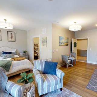 A modern and cozy open-plan bedroom and living area with stylish decor and wood flooring.