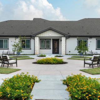 A modern single-story house with a landscaped garden and seating area.