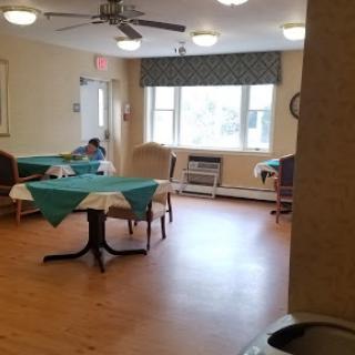 A spacious dining area with tables set for meals, featuring natural light from a large window.