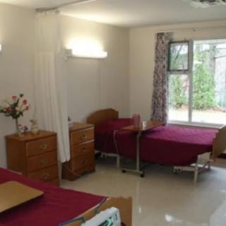 A hospital room with two patient beds and basic furnishings.