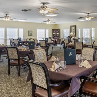 A well-arranged dining room with tables set for service, featuring ceiling fans and elegant decor.
