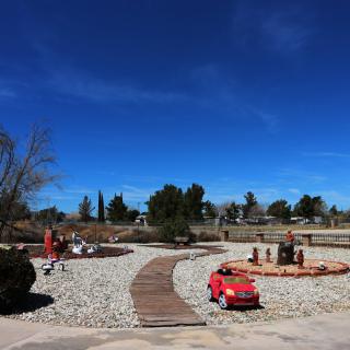 A scenic outdoor park featuring a winding pathway, sculptures, and clear blue skies.