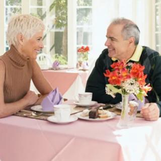 An elderly couple enjoying a conversation over tea in a cozy setting.