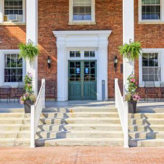A symmetrical building entrance with steps, columns, and decorative plants.
