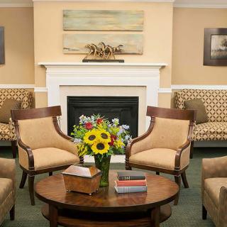 A cozy living room with a fireplace, featuring comfortable seating and a bouquet of sunflowers on the coffee table.