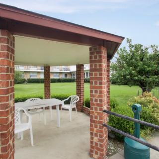 A brick gazebo with white furniture overlooks a lush green landscape.