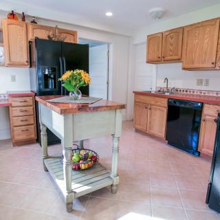 A bright and inviting kitchen with wooden cabinets, a central island, and modern black appliances.