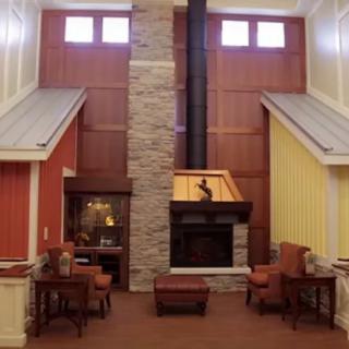 A modern living room with a high ceiling and central fireplace, featuring rustic decor elements.