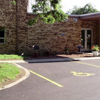 A handicapped accessible parking area in front of a stone building with outdoor seating.
