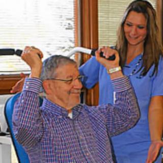 An elderly man engages in exercise with the assistance of a healthcare worker in a rehabilitation setting.