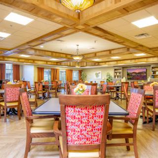 A spacious and inviting dining area featuring wooden beams and colorful chairs, perfect for social gatherings.