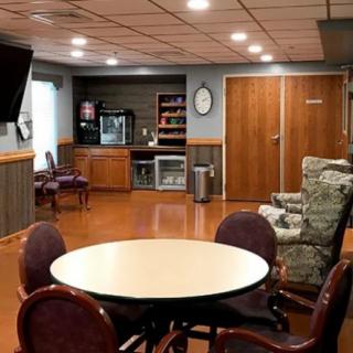 A cozy lounge area featuring a round table with chairs, an armchair, and amenities like a vending machine and television.