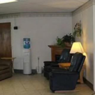 A cozy waiting room with recliner chairs, a sofa, a water cooler, and warm lighting.