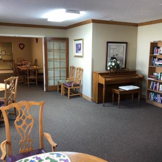 A cozy room with a piano, bookshelf, and seating area.