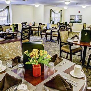 A well-decorated dining room with neatly arranged tables and chairs, featuring elegant table settings and floral centerpieces.