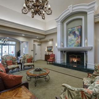 A cozy living room with a fireplace, elegant chandelier, and comfortable seating.