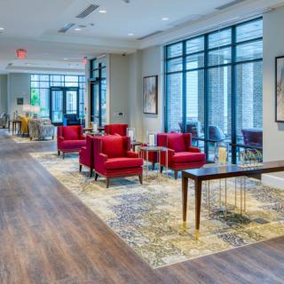 A modern lobby featuring red chairs and large windows, with artwork adorning the walls.