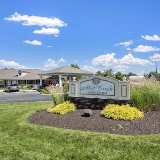 A welcoming entrance sign surrounded by lush landscaping under a bright blue sky.