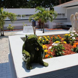A garden with colorful flowers and a frog sculpture.