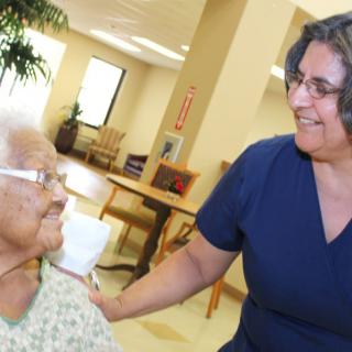 A caregiver interacting warmly with an elderly person in a nursing home setting.