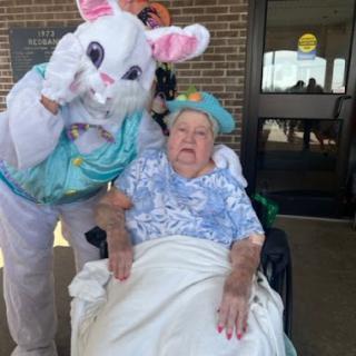 A joyful moment during an Easter celebration, featuring a person in a bunny costume with an elderly woman in a wheelchair.