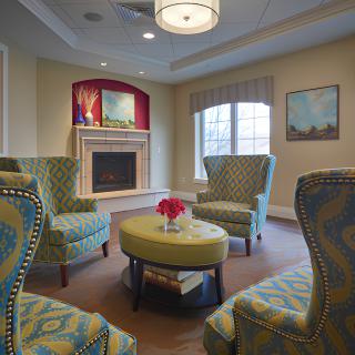 A cozy living room with patterned armchairs, a fireplace, and a circular table.