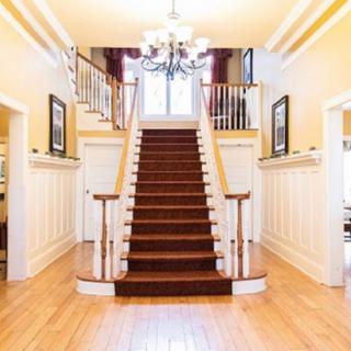 A grand staircase in a brightly lit foyer with decorative wainscoting and a chandelier.