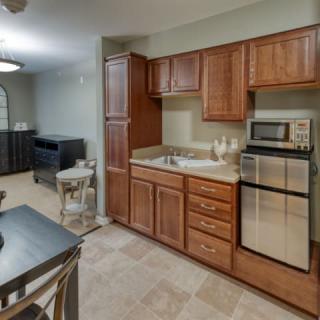 A cozy kitchen with wooden cabinets, a microwave, and a compact refrigerator, adjacent to a small dining area.