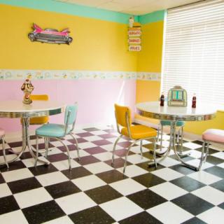 A retro-style diner with vibrant pastel walls and a classic black-and-white checkered floor.